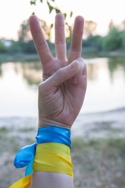 blue-yellow ribbons on the hands, the flag and the trident of Ukraine