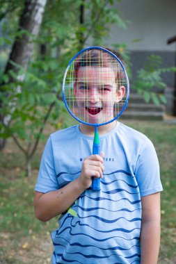 a boy with a badminton racket, a boy plays badminton on the background of the house