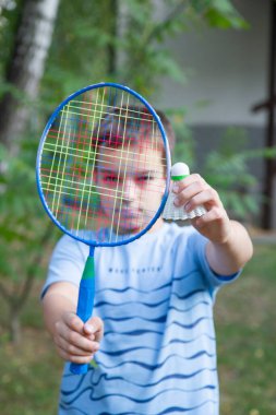 a boy with a badminton racket, a boy plays badminton on the background of the house