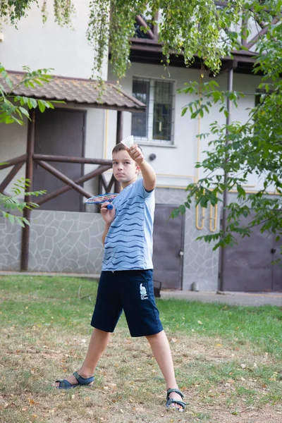 a boy with a badminton racket, a boy plays badminton on the background of the house