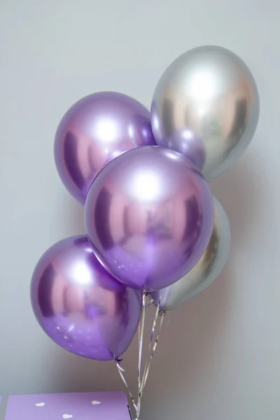 Duvarın arka planında mor ve gümüş renkli krom lateks balonlar