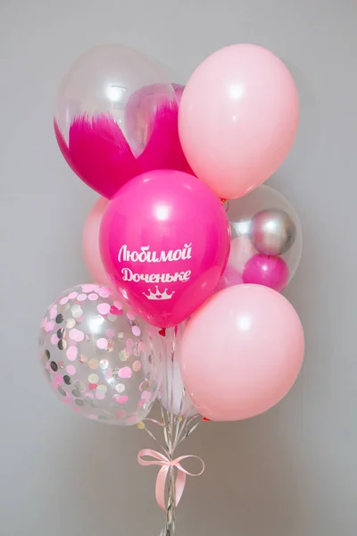 A set of pink balloons on the background of the wall, decor from helium balloons, the inscription on the pink foil balloon heart \