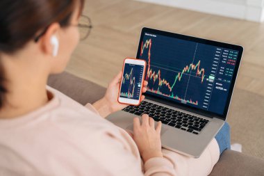 Ticari kadın borsa yatırımcısı analizcisini kapatın. Finansal piyasa değerleri dinamik, şifreli para birimi dijital analizleri için dizüstü bilgisayar ve akıllı telefon uygulaması kullanarak, kripto para birimi satın alarak.