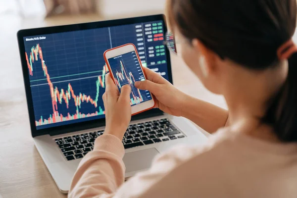 Akıllı telefon uygulaması ve dizüstü bilgisayarı kullanarak kripto para alıp satmak için borsa alım-satımı yapan kadın bir kripto simsarı. Seçici olarak eller ve cep telefonu ekranına odaklan