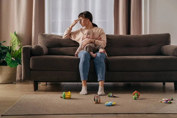 Doğum sonrası depresyondan muzdarip bekar bir anne. Bitkin düşmüş bir kadın bebeğini dizlerinin üstünde tutuyor, uykusuz geceler ve stresli annelik sorunları yüzünden stresli.