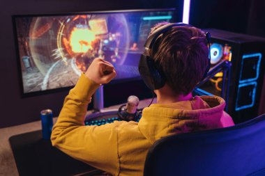 Profesyonel oyuncu kulaklık takarak online esport turnuvasında kazandığı zaferi kutluyor.