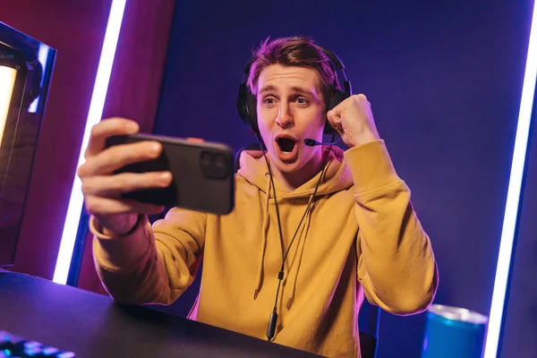 Pro gamer with headphones exited with winning in online mobile game