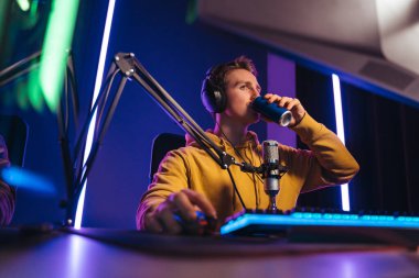 Profesyonel oyuncu gece bilgisayar oyunu oynarken enerji içeceği içiyor.