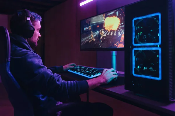 Pro gamer splaying multiplayer computer video game in dark neon room — Stok fotoğraf