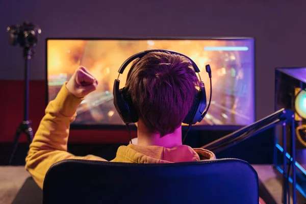 Back view of cyber sportsman rejoices his winning in online esport competition