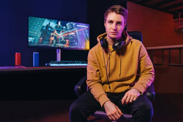 Portrait of serious young pro gamer sitting by gaming setup — Stockfoto