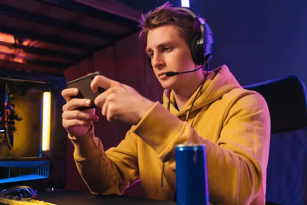 Young pro gamer playing in online mobile video games in neon coloured room — Fotografia de Stock