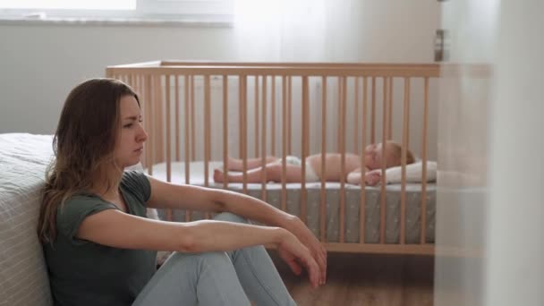 Young Mother Suffering Postnatal Depression Sitting Floor Next Baby Napping — Vídeo de stock
