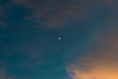 Altın renkli bulutlarla gün batımı gökyüzü ve mavi gökyüzünde parlak ay..