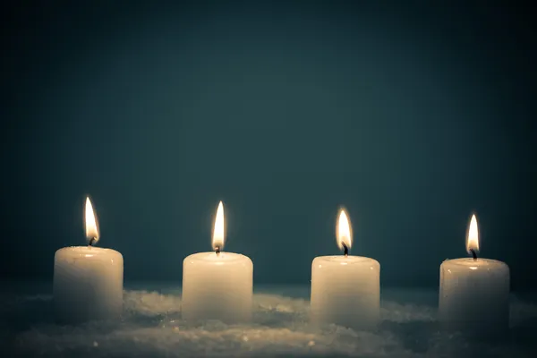Quatro velas brancas na neve — Fotografia de Stock
