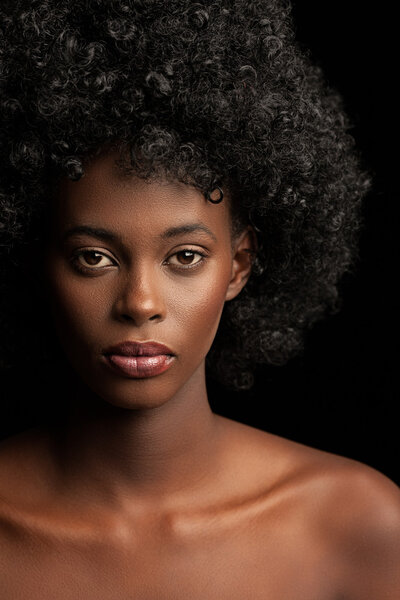 Beautiful young African woman posing against a black background.