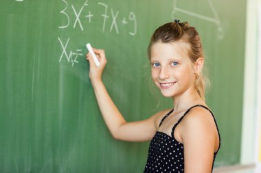 Okullu kız tahtaya yazı yazıyor.