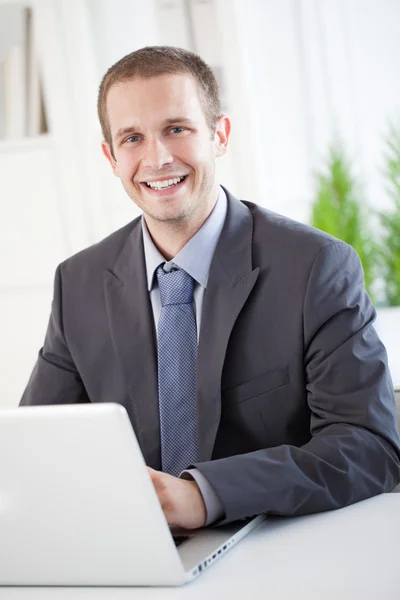 Χαμογελώντας επιχειρηματία που κάθεται στο φορητό υπολογιστή του — Φωτογραφία Αρχείου