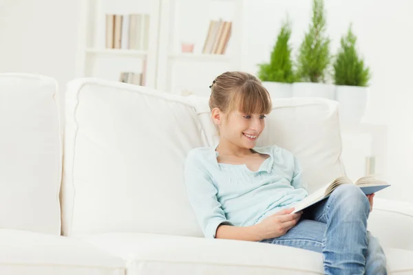 Chica sonriente leyendo un libro en casa — Foto de Stock
