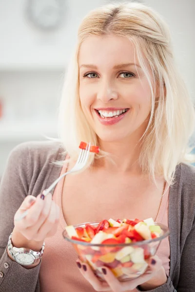 Femme souriante mangeant une salade de fruits — Photo