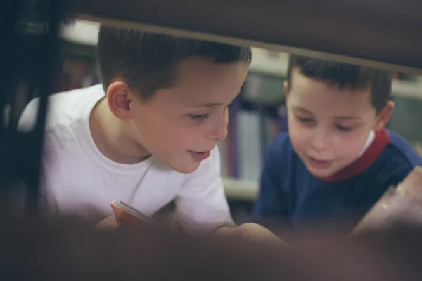 Pojkar söker böcker på biblioteket — Stockfoto