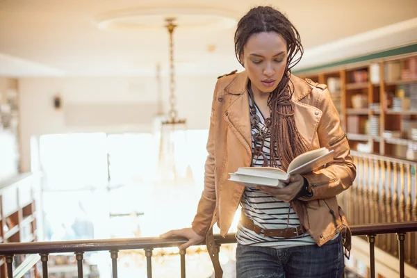 Femme afro-américaine lisant un livre à la bibliothèque — Photo