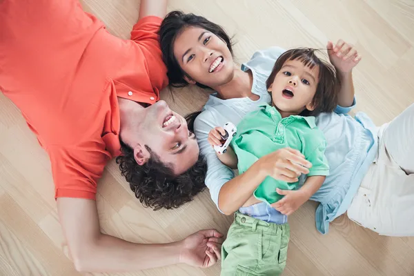 Família feliz deitada no chão — Fotografia de Stock