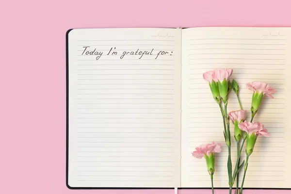 Top view of flowers on open paper notebook with handwritten words Today Im grateful for