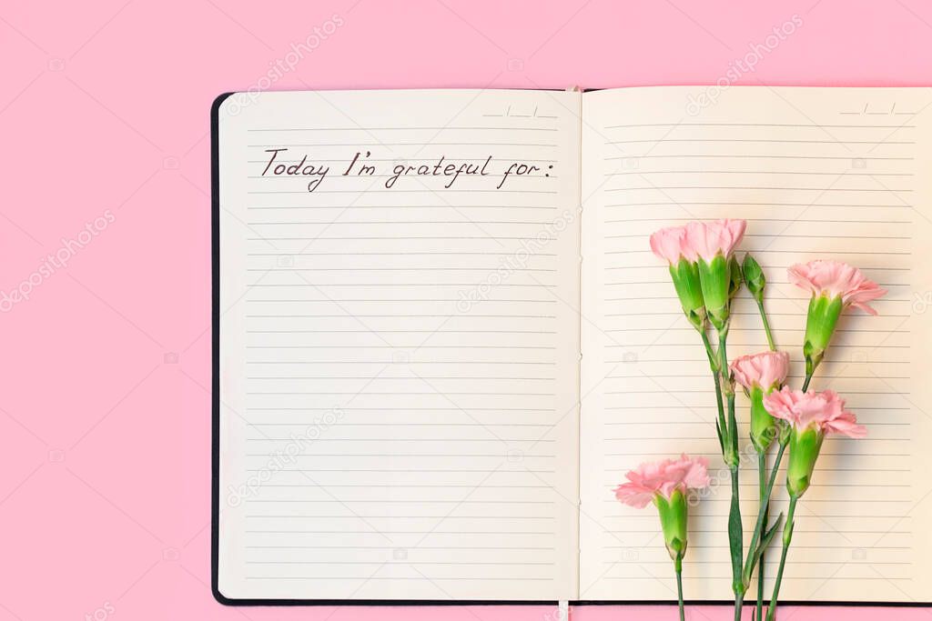 Top view of flowers on open paper notebook with handwritten words Today Im grateful for