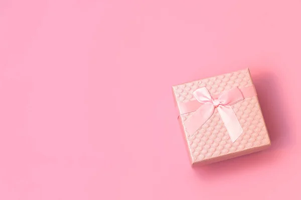 Pastel pembe arka planda saten fiyonklu pembe hediye kutusu ve fotokopi alanı. Düğün, doğum günü, mutlu kadınlar günü, anneler günü için beste.,