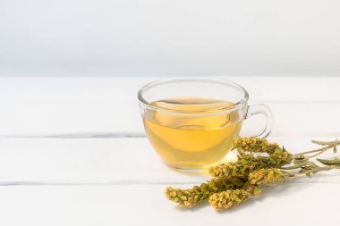Mursalski Chai ile bir bardak bitki çayı ve beyaz ahşap masada kurutulmuş otlar.