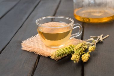 Bulgar Dağ Çayı Mursalski Çayı, koyu ahşap masa üzerinde kurumuş yapraklı cam bir fincanda.