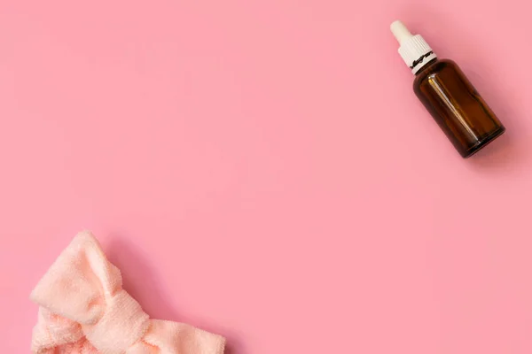 Flache Lagekomposition mit kosmetischer Flasche Serum oder Öl und Stirnband auf pastellrosa Hintergrund — Stockfoto