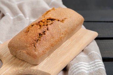 Koyu ahşap masada kesilmiş bir somun ev yapımı ekşi ekmek.