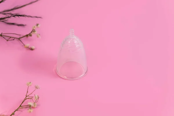 Cangkir menstruasi yang dapat digunakan silikon pada latar belakang merah muda lembut dengan bunga — Stok Foto
