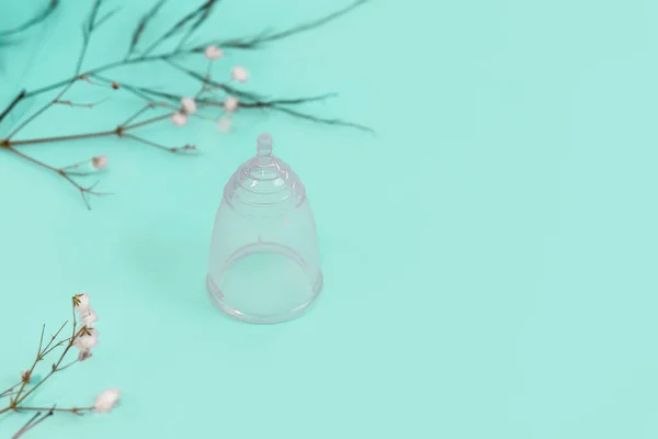 Silikon ramah lingkungan cangkir menstruasi dapat digunakan kembali pada latar belakang mint cahaya dengan bunga-bunga kecil — Stok Foto