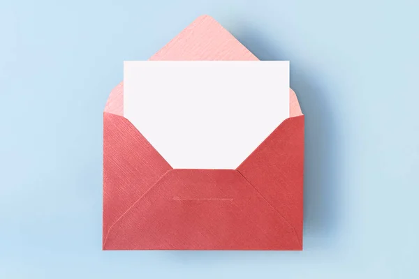 薄い青の背景に空の空白の白いカードと赤い封筒のトップビュー — ストック写真