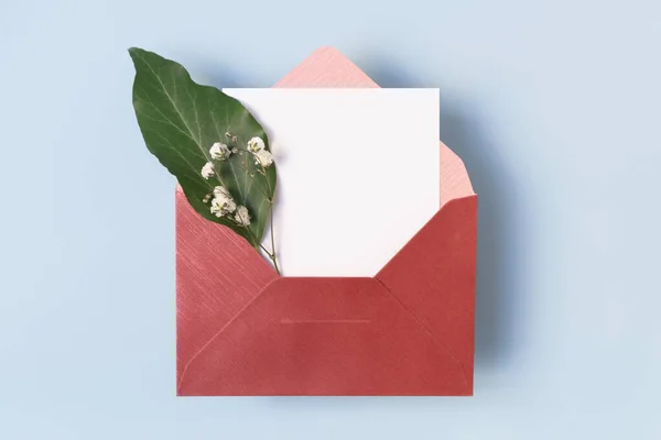 ライトブルーの背景に花と白の空白のカードを持つオープンエンベロープ コピースペース トップビュー — ストック写真
