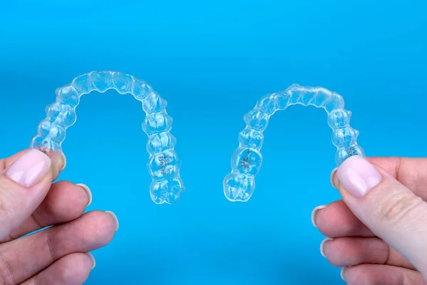 Transparent invisible brackets invisalign braces. Female caucasian hands holding two plastic aligners or retainers — Stock Photo, Image