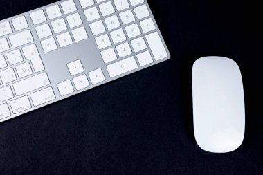 Beyaz ve gümüş klavye ve fare siyah arkaplan üst görünümü.
