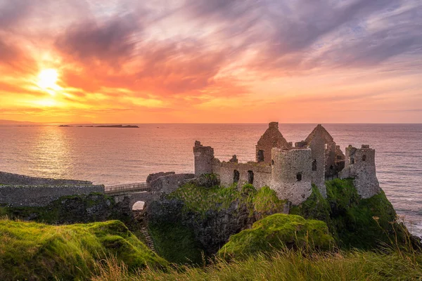 Bushmills uçurumundaki Dunluce Şatosu, gün batımı