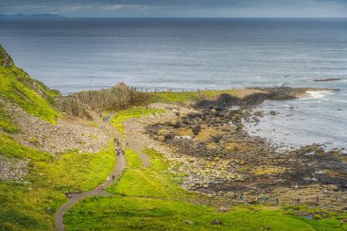 Giants Causeway, Wild Atlantic Way ve UNESCO 'nun dünya mirası Kuzey İrlanda' da ana altıgen kaya oluşumunda turistler görülüyor.