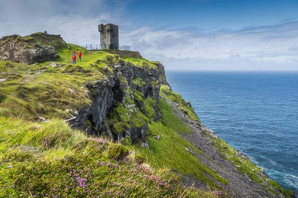 Turistas visitando Moher Tower en Hags Head, Acantilados de Moher, Irlanda Fotos de stock