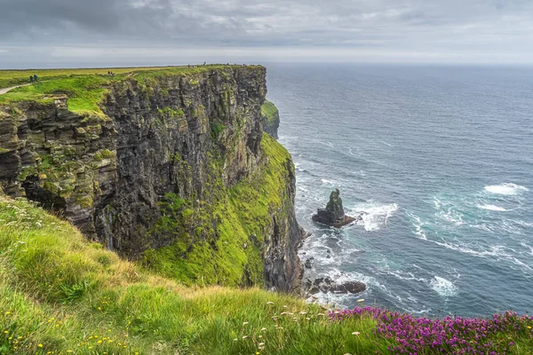 People hiking on the edge of iconic Cliffs of Moher, Ireland — Foto de Stock