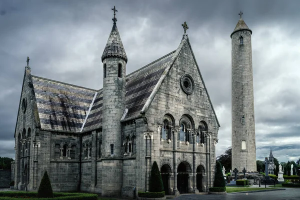 Güzel, Kelt haçı ve Glasnevin Mezarlığı 'ndaki Yuvarlak Kule' ye sahip antik bir mozole, arka planda dramatik fırtına gökyüzü, Dublin, İrlanda
