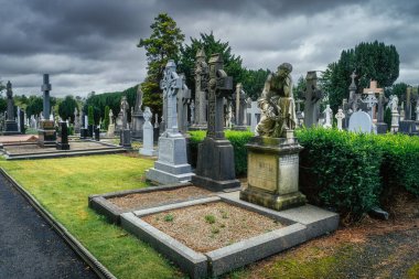 Dublin, İrlanda, Ağustos 2019 Arkaplanda dramatik fırtına gökyüzü olan Glasnevin Mezarlığı 'nda Kelt haçları ve heykelleriyle antik mezarlar