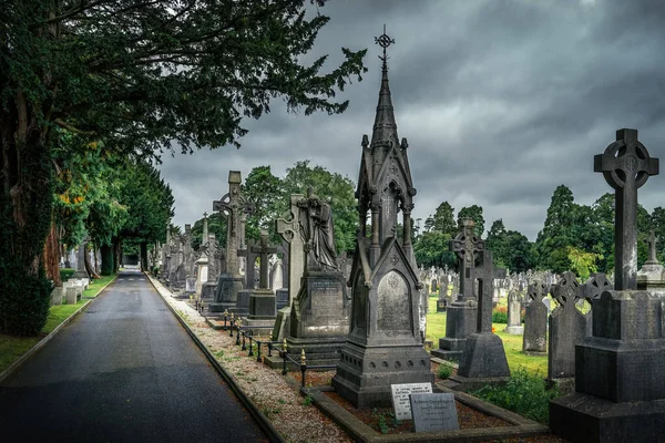 Dublin, İrlanda, Ağustos 2019 Arkaplanda dramatik fırtına gökyüzü olan Glasnevin Mezarlığı 'nda Kelt haçları ve heykelleriyle antik mezarlar