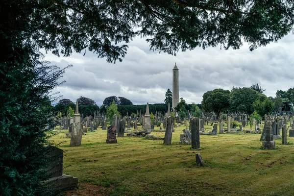 Tumbas y lápidas antiguas en Cementerio Glasnevin con Round Tower, Irlanda Fotos de stock