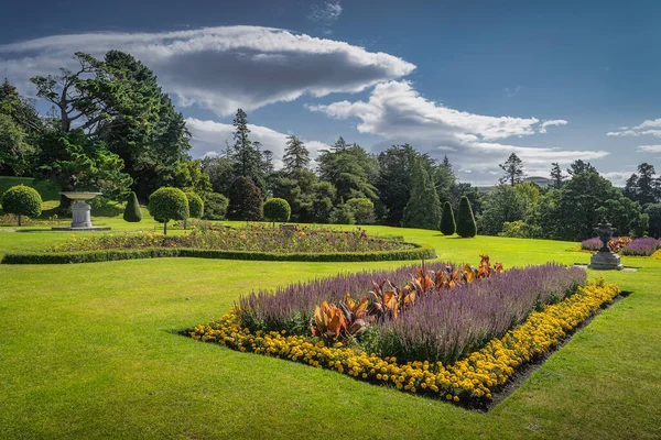 Jardin Powerscourt avec parterres de fleurs, haies, arbres décoratifs, fontaines et forêt en arrière-plan, Irlande — Photo