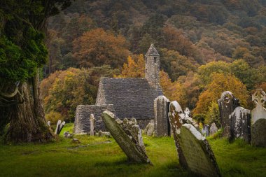 Ortaçağ kilisesi, antik mezarlar, Glendalough Mezarlığı 'nda Kelt haçları sonbahar ormanı ve yağmur altında dağlar, Wicklow, İrlanda